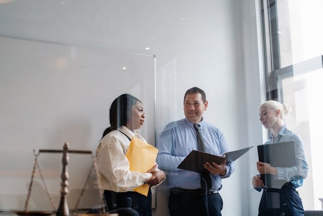 Business professionals discussing real estate market insights, with documents in hand, in a modern office setting, reflecting the dynamic nature of the Beaches Town Center real estate landscape.