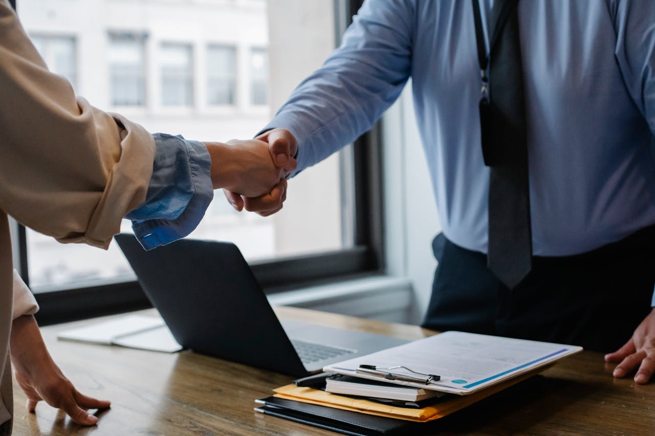 Business professionals shaking hands in an office setting, symbolizing partnership and investment opportunities in the Oceanwalk real estate market.